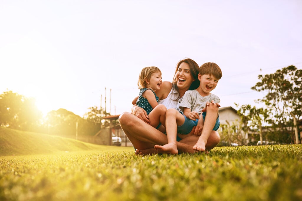 Woman and children laughing together on grass